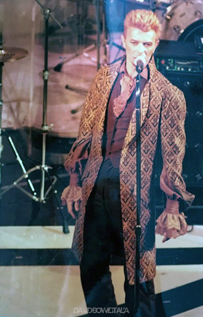 David Bowie a Sanremo | 20 Febbraio 1997 3 David Bowie al microfono con la lunga redingote a gigli, Sanremo 1997